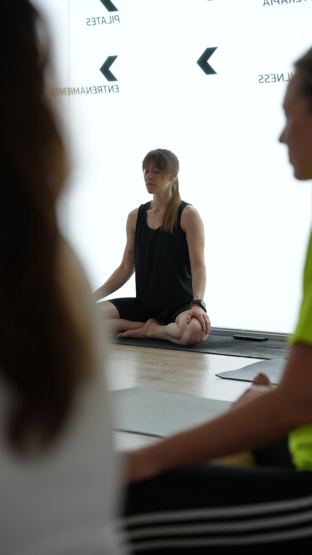 Práctica de yoga en grupo guiada por una instructora de FisioFit