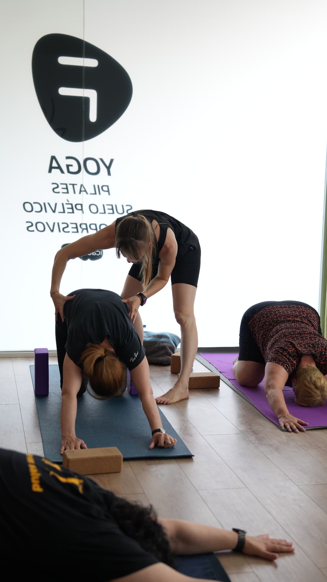 Instructora acompañando de forma individual una postura de yoga
